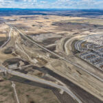 The western extent of the Highway 22X corridor with earthworks in the foreground, as well as new road alignment in the median of Highway 22X and to the north (looking northwest)